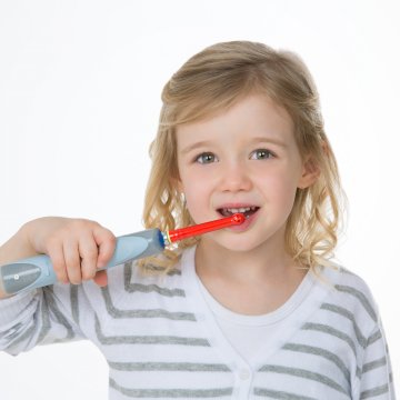 Young girl with electric toothbrush in her mouth